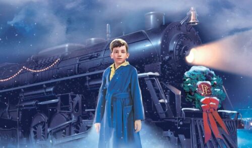 A still from an animated film in which a young boy in a blue dressing gown is stood in front of a large train