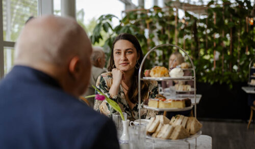 A man and a woman sat at a table having afternoon tea