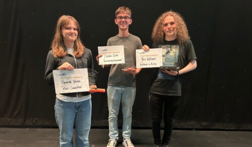 Three young people pose with certificates and awards
