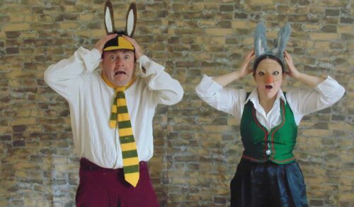 Two actors wearing donkey ears look shocked at the camera