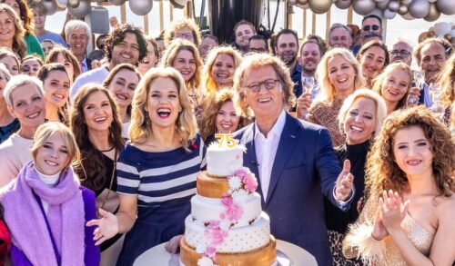 A crowd of people gather around a large cake with the number 75 on top of it