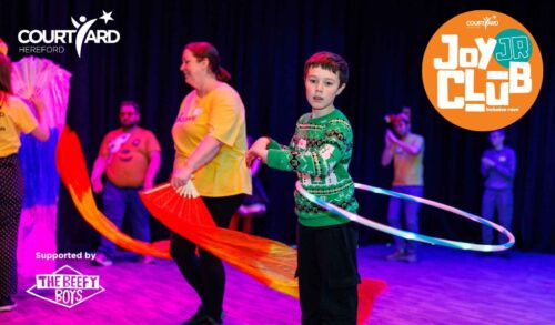 A group of young people with special educational needs and disabilities dancing and playing in a room with multicoloured lights