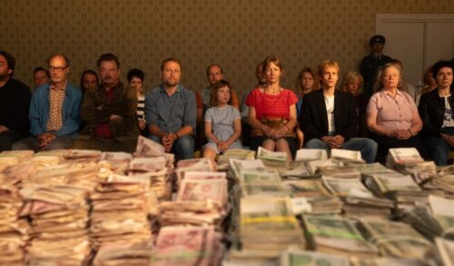 Two To One  a varied group of people sit in front of piles of cash