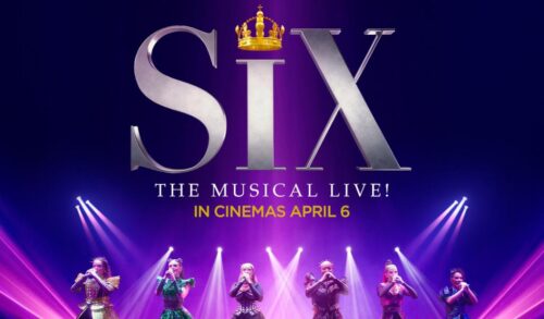 A theatre stage lit with pink and purple lights On the stage are 6 women in colourful 16th century clothing perform with microphones A large title reads Six the Musical Live and the dot of the i has been replaced with a crown