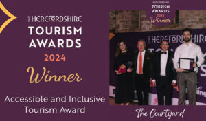 Herefordshire Tourism Awards 2024 Winner: Accessible & Inclusive Tourism Award - The Courtyard written on a purple background next to a photo of 3 men and a woman smiling and holding a glass award